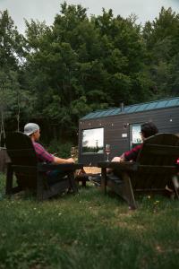 two people sitting on benches in front of a tiny house at TogetherNest - Ash in Mătişeşti