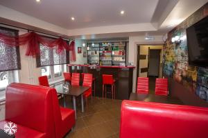 シェレゲシュにあるZima-Leto Hotelの赤い椅子とテーブルのあるレストラン、バー