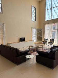 a living room with two black couches and a tv at Belle Villa Kassonyah, Conakry in Conakry