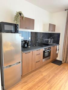 a kitchen with a stainless steel refrigerator and wooden cabinets at Le Cosy in Dunkerque