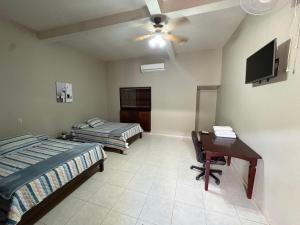a bedroom with two beds and a desk and a television at Dormitorio in Juticalpa