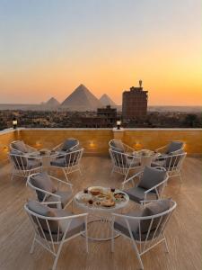 a rooftop patio with chairs and tables with pyramids in the background at Royal Pyramids Hotel in Cairo