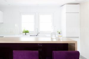 a kitchen with a counter with two purple chairs at Leśna Willa ŚWIT in Holendry