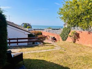 a bench in a yard with the ocean in the background at Peaceful Coastal Escape in Old Colwyn