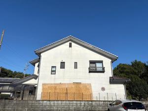 a white building with boarded up windows on it at Anan Seaside House in Anan