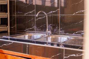 a stainless steel sink in a kitchen with black tiles at Elikai Hostels 