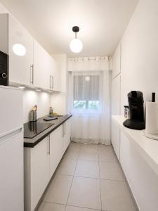 a white kitchen with white cabinets and a window at LorOtel - Frontiere - Aeroport in Saint-Louis