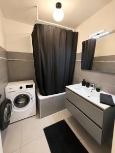 a bathroom with a washing machine and a sink at LorOtel - Frontiere - Aeroport in Saint-Louis