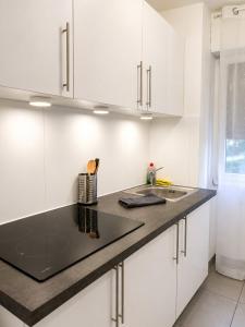 a kitchen with white cabinets and a black counter top at LorOtel - Frontiere - Aeroport in Saint-Louis