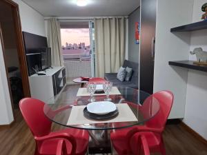 a dining room with a glass table and red chairs at Flat à beira mar, charmoso e aconchegante in João Pessoa