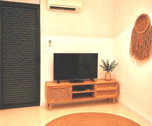 a living room with a flat screen tv on a wooden cabinet at Suites Aronas-hébergements climatisés rive droite plein centre ville in Le Grau-du-Roi
