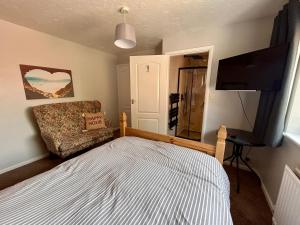 a bedroom with a bed and a chair and a flat screen tv at Peaceful Coastal Escape in Old Colwyn