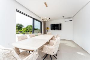 a white dining room with a white table and chairs at Villa Sunshine in Pridraga