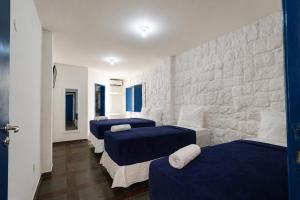 a room with three beds and a stone wall at Pousada Villa Grécia in Aracaju