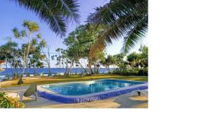a swimming pool next to a beach with a palm tree at Bluepango Guest House in Port Vila