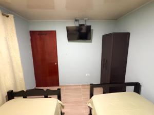 a room with two beds and a tv on the wall at posada nativa NIYKA in Casabaja
