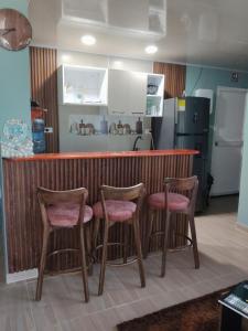 a kitchen with a bar with three stools at posada nativa NIYKA in Casabaja