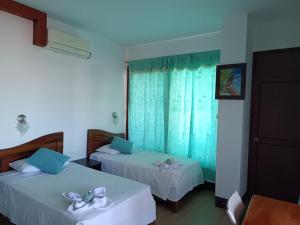 a hotel room with two beds and a window at Vami's House in Puerto Villamil