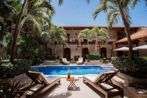 a courtyard with a swimming pool and palm trees at Hotel Plaza Colon - Granada Nicaragua in Granada