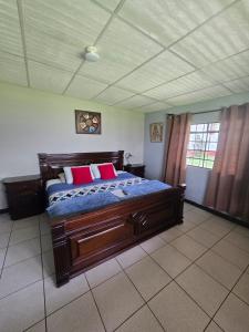 a bedroom with a large wooden bed with red pillows at El Refugio - Hospedaje y Eventos in San Lucas Sacatepéquez