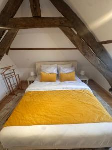 a bedroom with a large bed with a yellow blanket at Le loft sous les colombages in Gouffern en Auge
