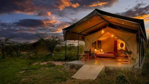 a tent with a bed in a field at sunset at Royal Horizon Adventure in Sekenani