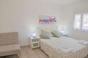 a white bedroom with a bed and a chair at Apartamento Aira in Villadepalos
