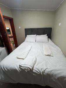a large white bed with white sheets and pillows at Lynch Apartments 2 - Mimosa Chilanga in Lusaka