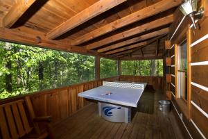 a ping pong table in the center of a wooden porch at Sugar Bear in Sevierville