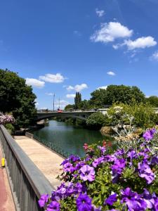 a river with purple flowers next to a bridge at Riverside Studio Joinville-Le-Pont in Joinville-le-Pont