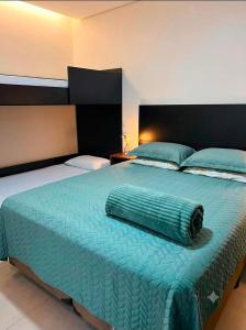 a large bed with a green blanket on top of it at A Oca Praiana Suites in Ilha Comprida