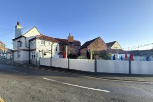 a house with a white fence next to a street at Lobster Sheringham in Sheringham