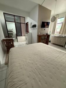 a bedroom with a large bed and a kitchen at KITNETS Kretzer Hinckel 1 - CENTRO in Alfredo Wagner