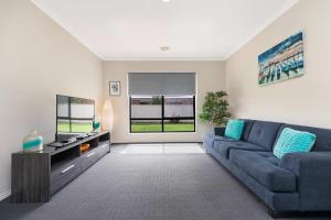 a living room with a blue couch and a tv at 28 Skye Ave - Skye High on Style in Moama