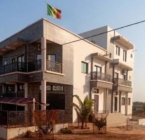 a building with a flag on top of it at Kër Mouna MJN Hotels in Diass