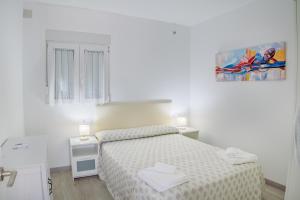 a white bedroom with a bed and two night stands at Apartamento Aira 2 in Villadepalos