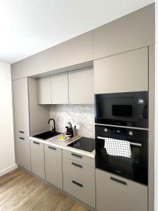 a kitchen with white cabinets and a black microwave at LOCAPONDI 5 - Les Reflets du Canal in Pontivy