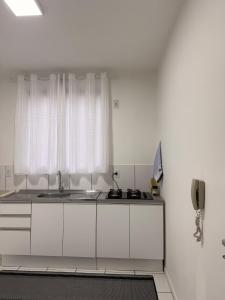 a white kitchen with a sink and a window at Spazio Cristalli Comfort in Cuiabá +12 photos