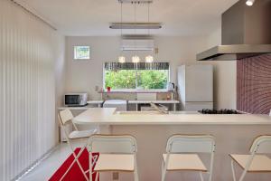 a kitchen with a white counter and chairs in it at Sea Shell Kawazu House in Kawazu