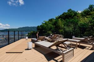 a deck with tables and chairs and a view of the water at HOTEL FORK & KNIFE Miyajima in Miyajima
