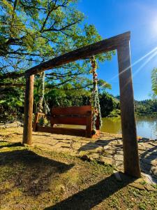 a wooden swing sitting next to a lake at Chalé Pé da Serra in Treviso +13 photos