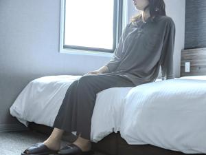 a woman sitting on a bed looking out the window at Super Hotel Tottori Station North Exit Smoke-Free in Tottori +84 photos