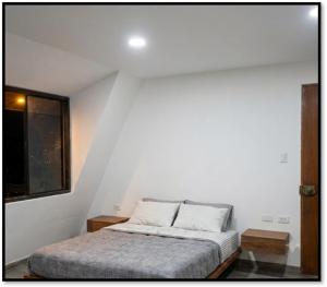 a bedroom with a bed in a white room at Cabañas Cavanilla in Oxapampa