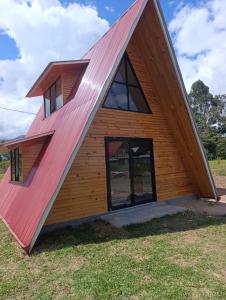 a timber clad house with a red roof at Cabañas Cavanilla in Oxapampa