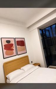 a bedroom with three paintings on the wall and a bed at Collins unique apartments in Ruaka