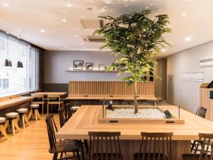 a tree in the middle of a room with tables and chairs at Super Hotel Morioka in Morioka
