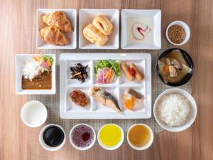 a table with plates of food and bowls of food at Super Hotel Morioka in Morioka