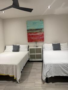 two beds in a room with a painting on the wall at Sol y mar in Rosarito Beach