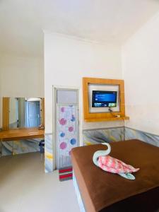 a room with a bed and a tv on a wall at PONDOK CHILLY in Cirebon