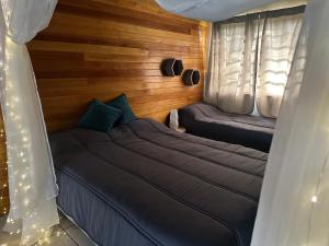 two beds in a room with wooden walls and curtains at Refugio Viggena in Tandil